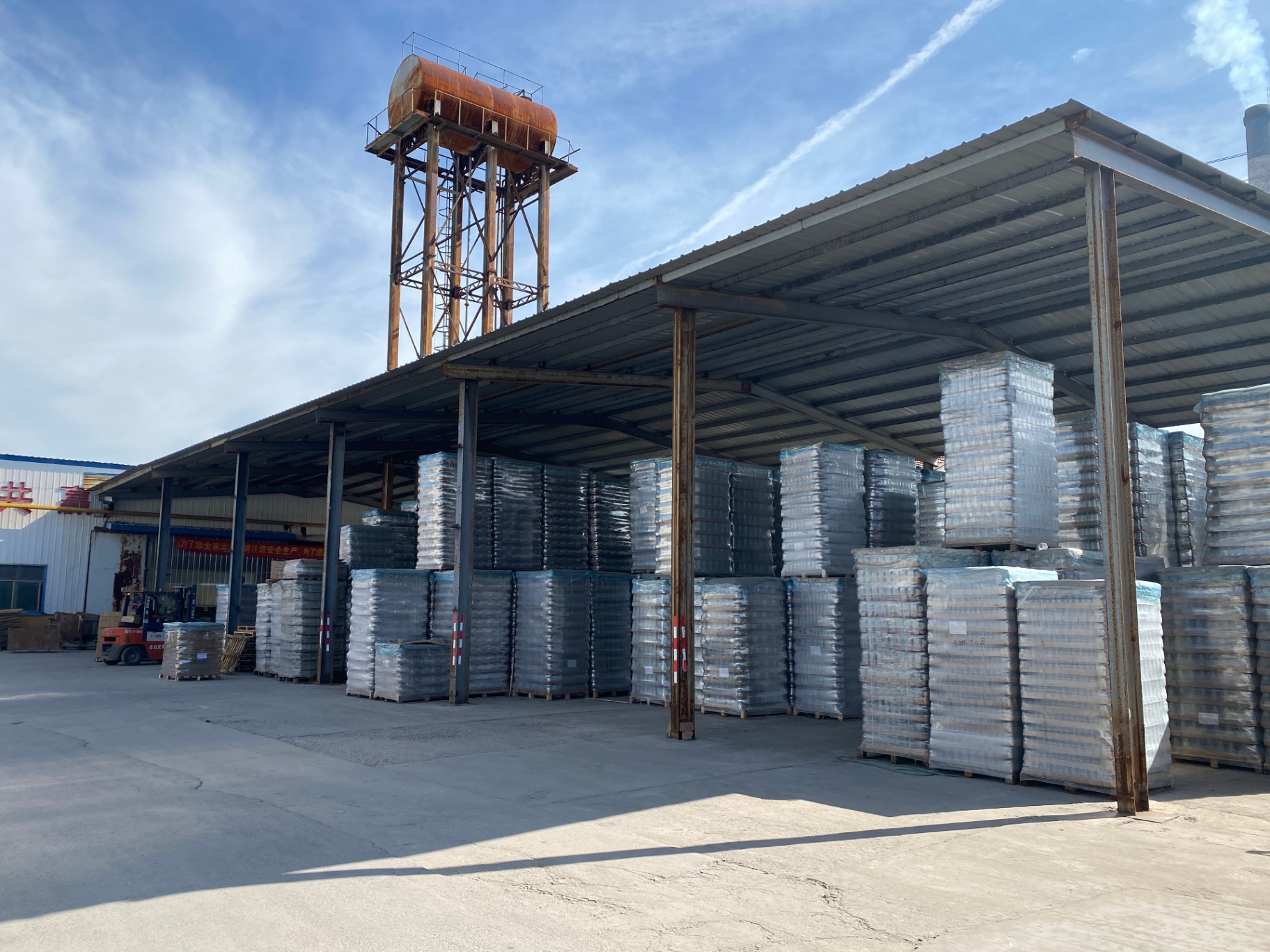 Outdoor covered storage yard with pallets of glass bottles awaiting container loading